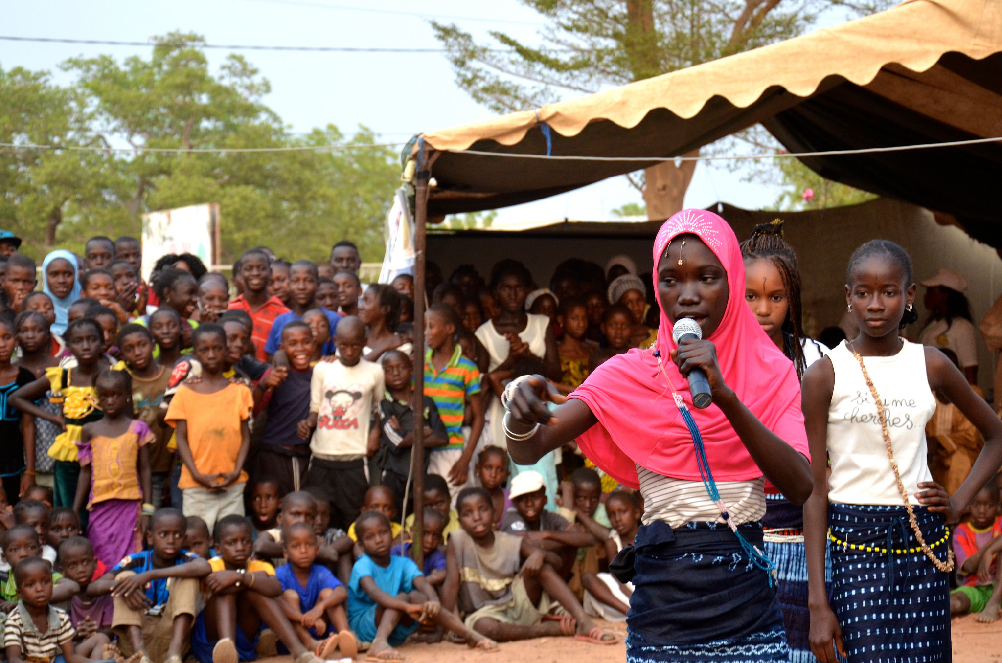 A cover picture for Youth Engagement Measurement Guideline. A young girl is speaking on a microphone and there are girl and boy children on the background. A cover picture for Youth Engagement Measurement Guideline. A young girl is speaking on a microphone and there are girl and boy children on the background.